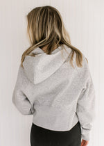 Back view of Model wearing an gray hoodie with a 1/4 zip, long sleeves and a front pouch pocket.
