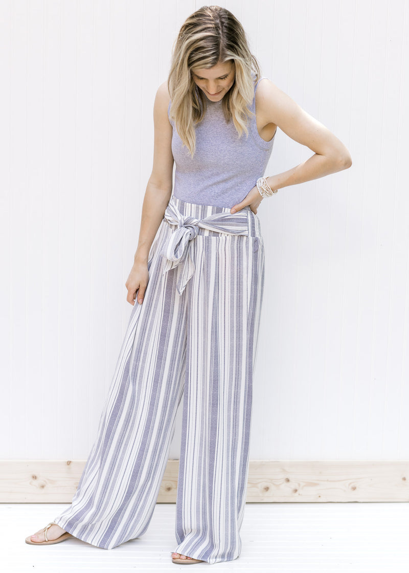 Model wearing striped pants with a ribbed gray sleeveless body suit with a mocked neckline. 