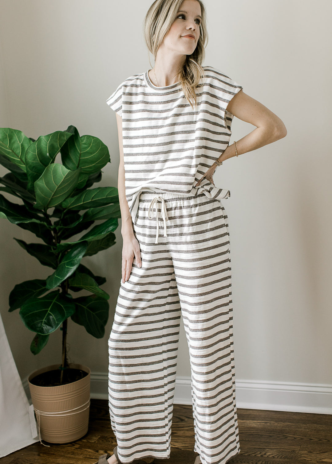 Model wearing sandals and a gray and white striped set with a short sleeve top and wide leg pants.