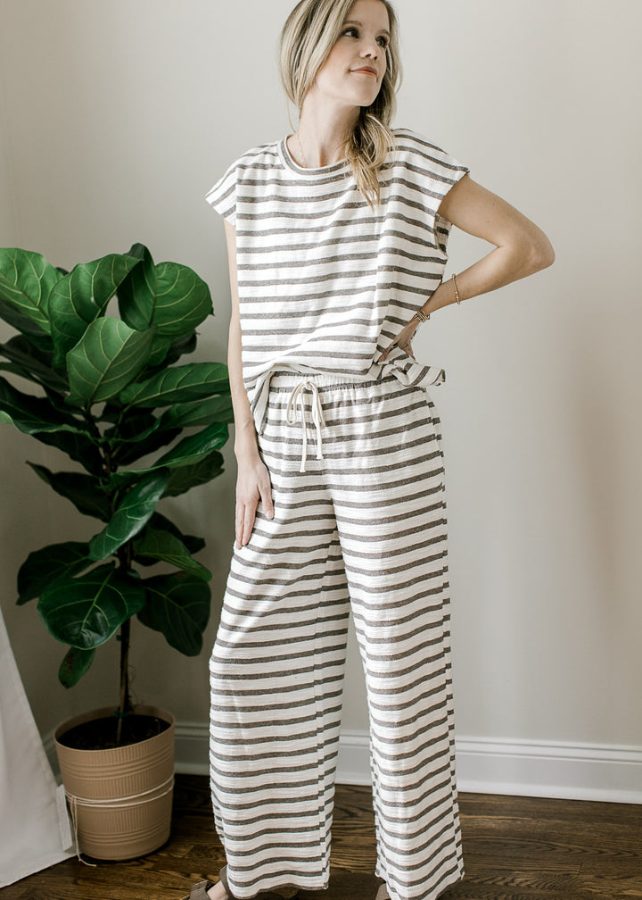 Model wearing sandals and a gray and white striped set with a short sleeve top and wide leg pants.
