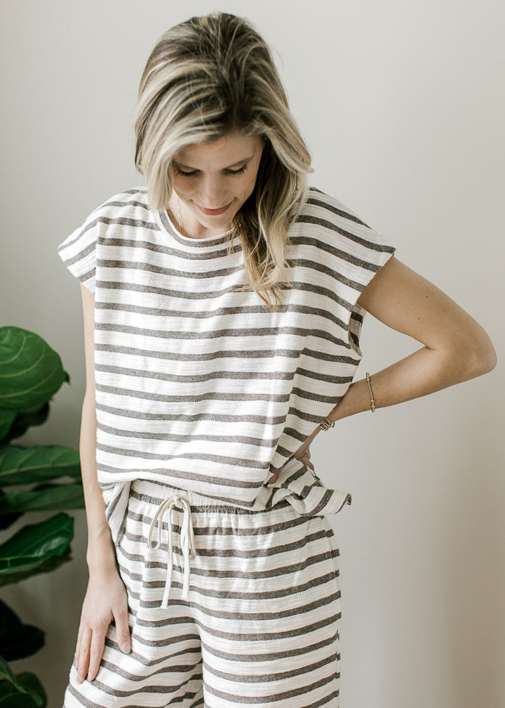 Close up on short sleeve top with round neck of a gray and white striped set with wide leg pants.