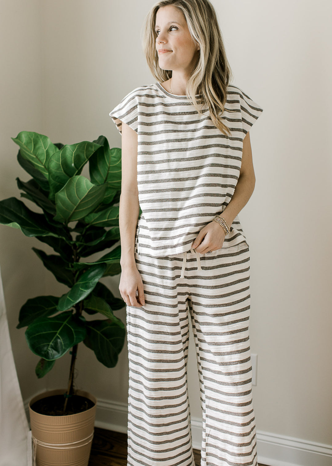 Model wearing a lounge set with gray adn white stripes, short sleeve top and wide leg pants. 