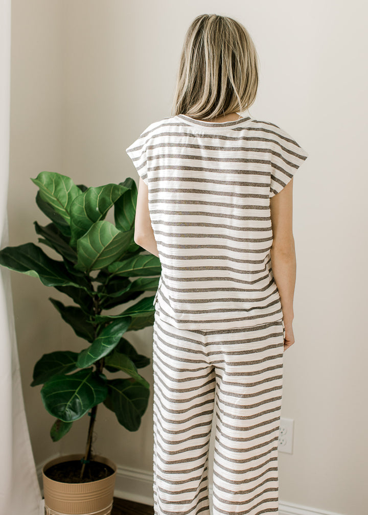 Back view of Model wearing a gray and white striped set with short sleeve top and wide leg pants.