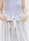 Close up view of front tie detail on gray and white striped wide leg pants. 