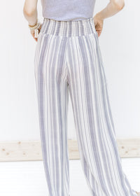 Back view of model wearing gray and white striped wide leg pants with elastic on the back. 