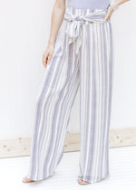 Model wearing gray and white wide leg pants with an elastic waist and front tie, made of polyester. 