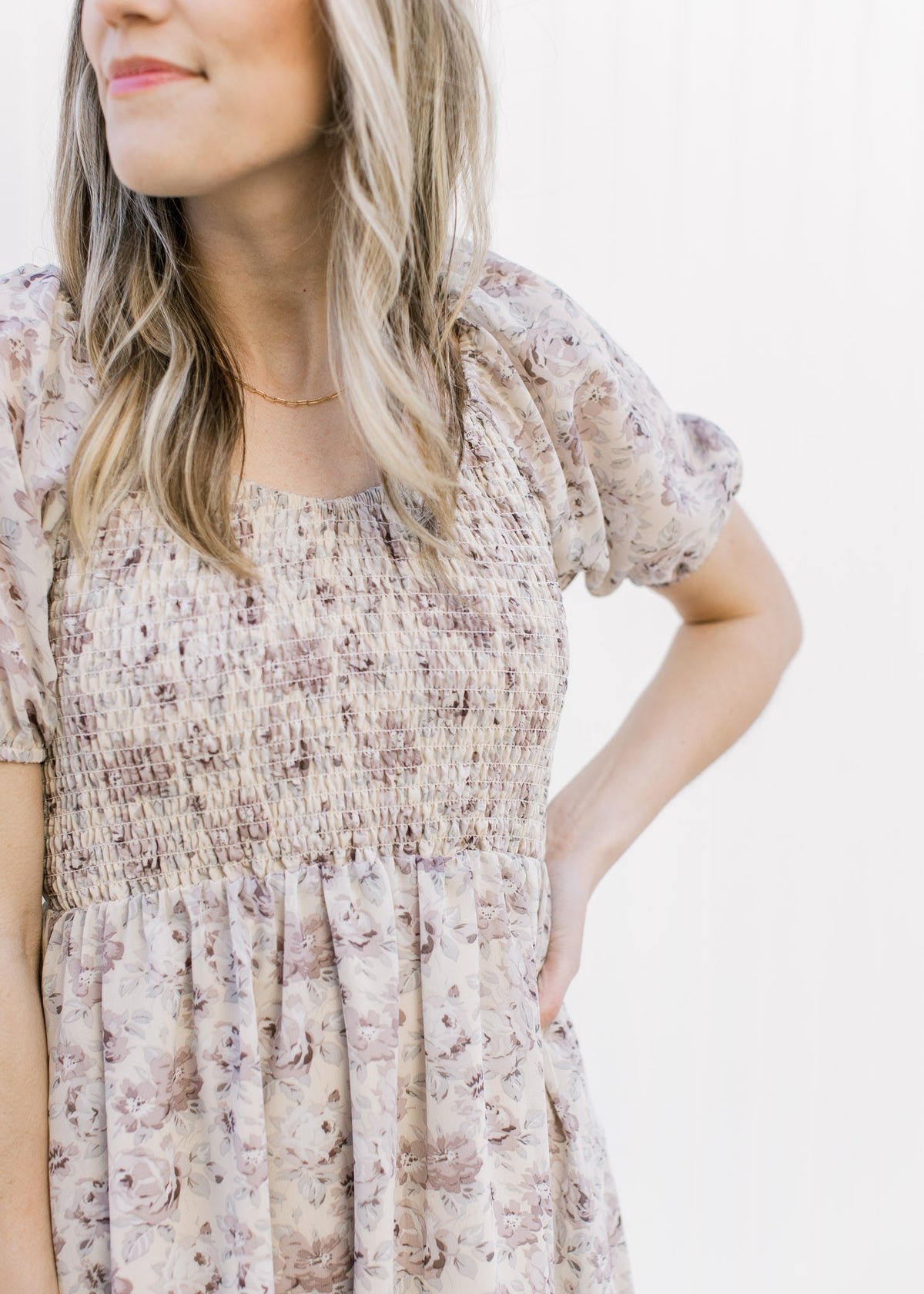 Close up of smocked bodice and bubble short sleeves on a gray dress with violet and blue flowers.