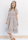 Model wearing heels with a gray floral dress with a smocked bodice and sheer bubble short sleeves.