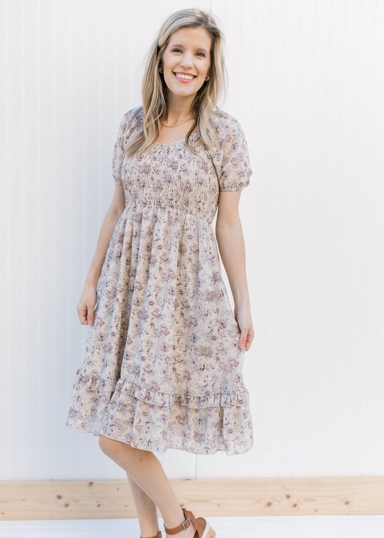 Model wearing heels with a gray floral dress with a smocked bodice and sheer bubble short sleeves.