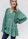 Model wearing jeans and a green v-neck top with wide long sleeves, tiered layers and a tunic length.