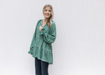 Model wearing a green acid washed top with wide long sleeves, tiered layers and a tunic length 