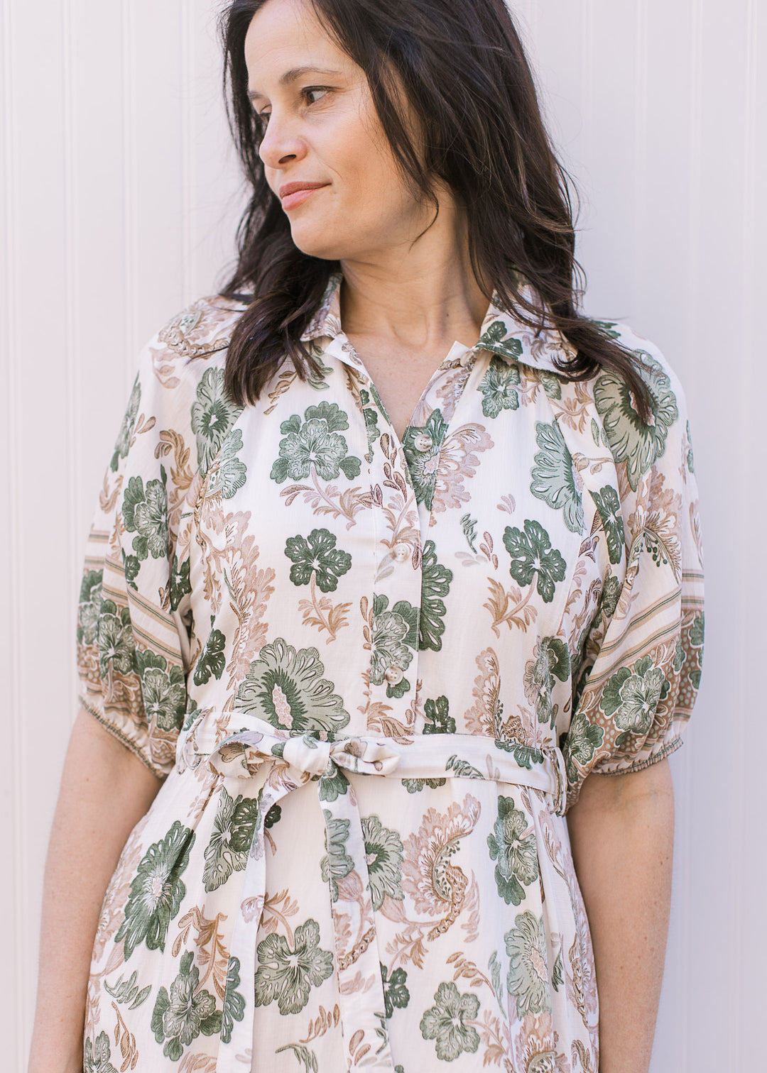 Model wearing a cream midi with green and tan floral, collar, button-front placket and tie at waist.