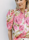 Close up of pleated short shoulders and buttons on a cream top with pink and green floral.