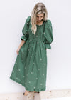 Model wearing a green midi with cream embroidered bows, a square neck, 3/4 poet sleeves and booties.