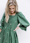 Close up of 3/4 poet sleeve on a green midi dress with cream embroidered bows and a smocked back.