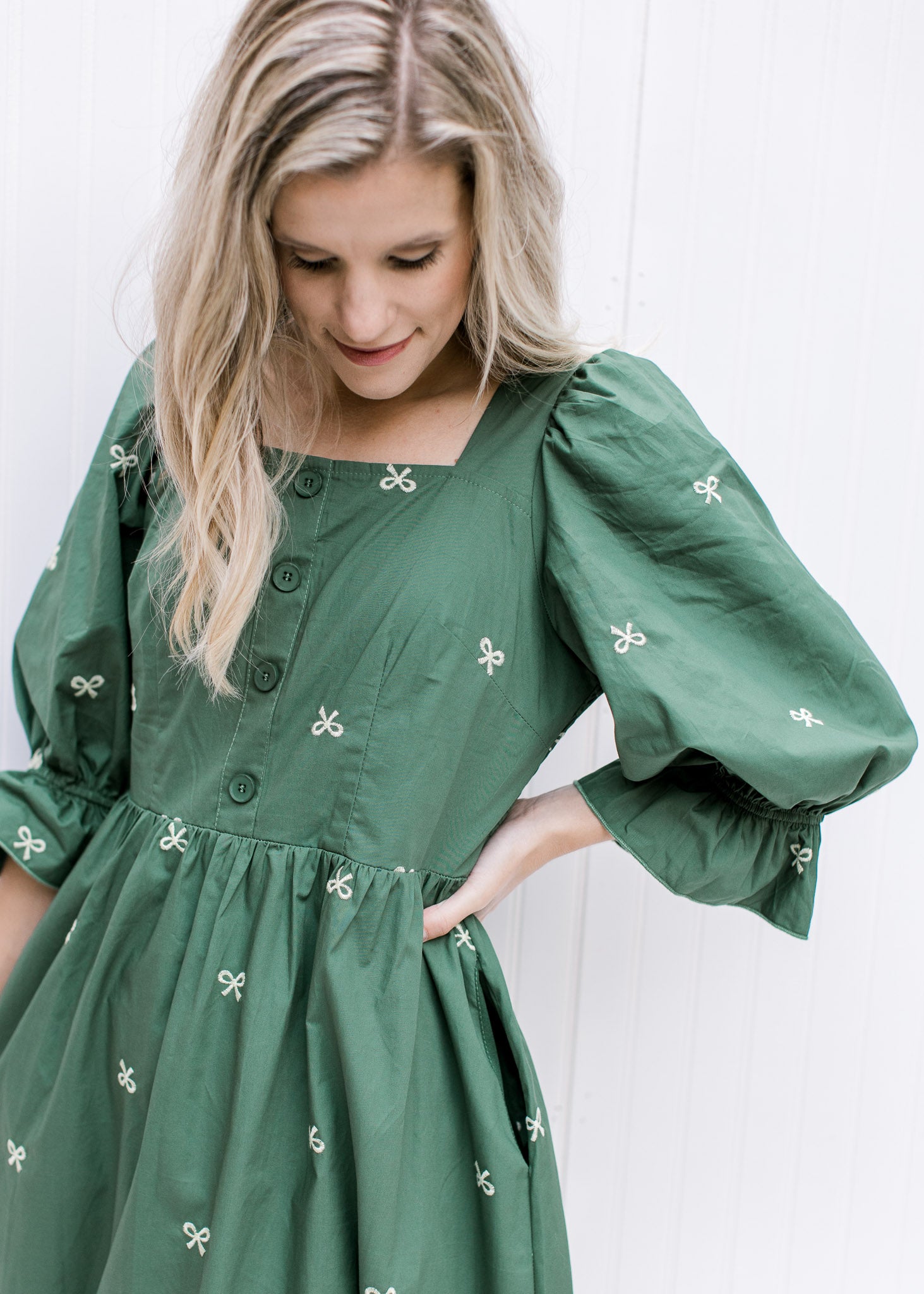 Close up of 3/4 poet sleeve on a green midi dress with cream embroidered bows and a smocked back.