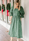 Model wearing a green midi with cream embroidered bows, a square neckline and 3/4 poet sleeves. 
