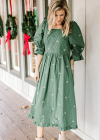Model wearing a green midi with cream embroidered bows, a square neckline and 3/4 poet sleeves. 