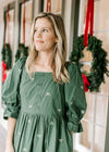 Model wearing a green dress with cream embroidered bows, a square Nike and 3/4 poet sleeves. 