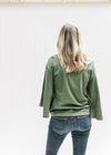 Back view of Model wearing an olive top with 3/4 butterfly sleeves, a round neck and cotton material