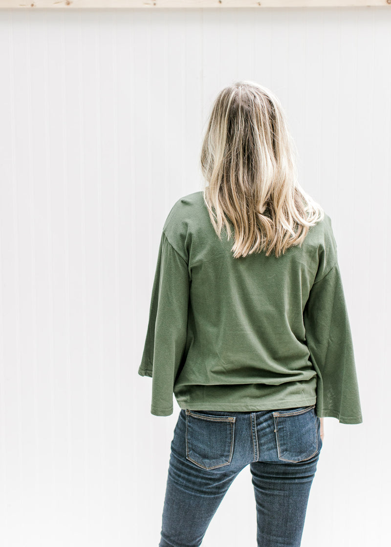 Back view of Model wearing an olive top with 3/4 butterfly sleeves, a round neck and cotton material