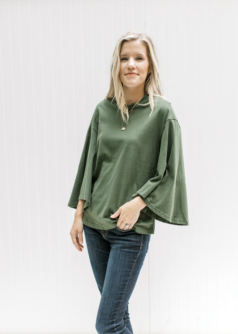 Model wearing an olive top with 3/4 butterfly sleeves, a round neck and a cotton material.