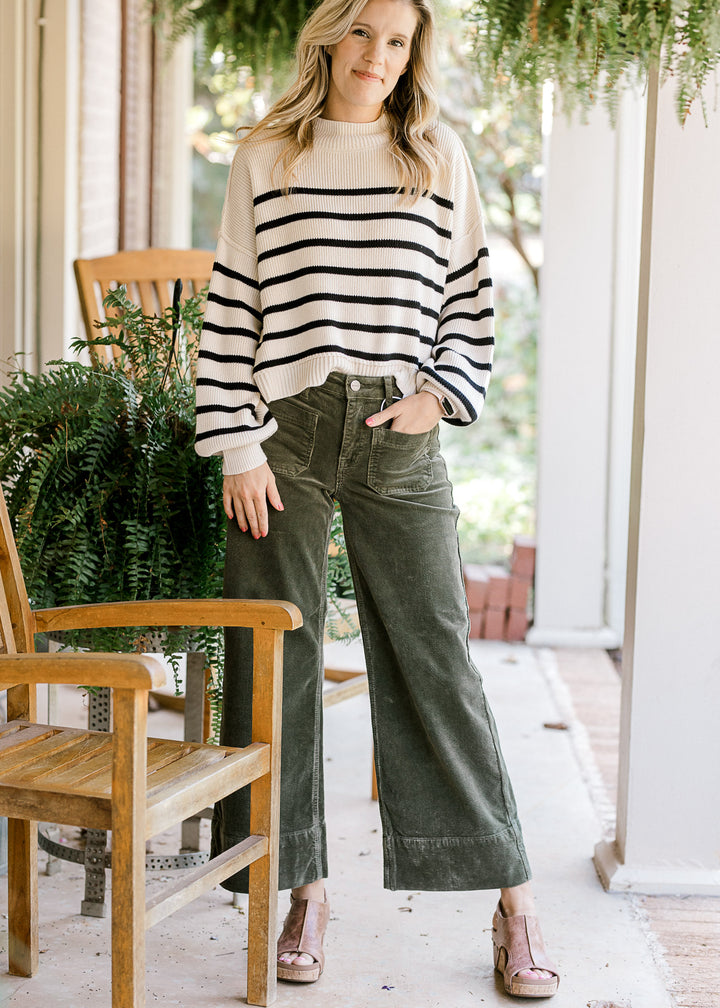 Model wearing green corduroy cropped pants with front patch pockets and traditional button. 