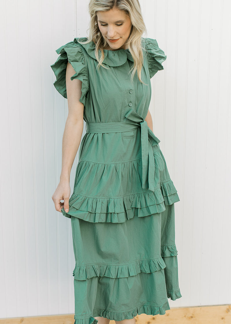 Model wearing a deep green midi with ruffle collar, sleeves and double ruffles on skirt.