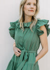 Close up of tie waist, buttons ad ruffle at neck and sleeve of a deep green midi with pockets.