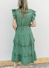 Back view of Model wearing a deep green midi with ruffle collar, sleeves and double ruffle on skirt.