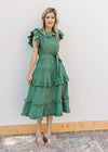 Model wearing wedges and a deep green midi with ruffle collar, sleeves and double ruffles on skirt.