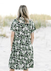 Back view of model wearing a black dress with a green and cream floral patter and short sleeves.