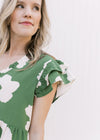 Close up of ruffle layered cap sleeves on a green above the knee dress with cream flowers.