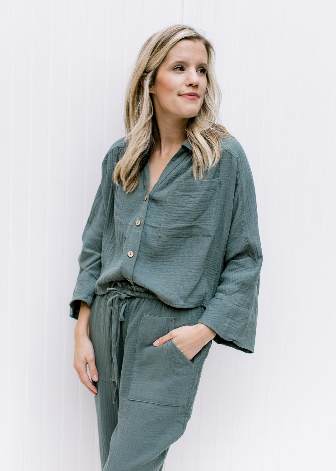 Model wearing a hunter green gauze set, top with button closure and crop fit, bottom with tie waist.