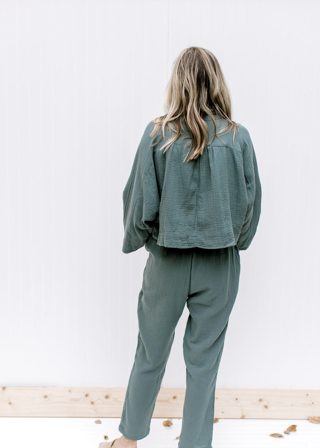 Back view of Model wearing a hunter green gauze set, top with crop fit, bottom with tie waist.