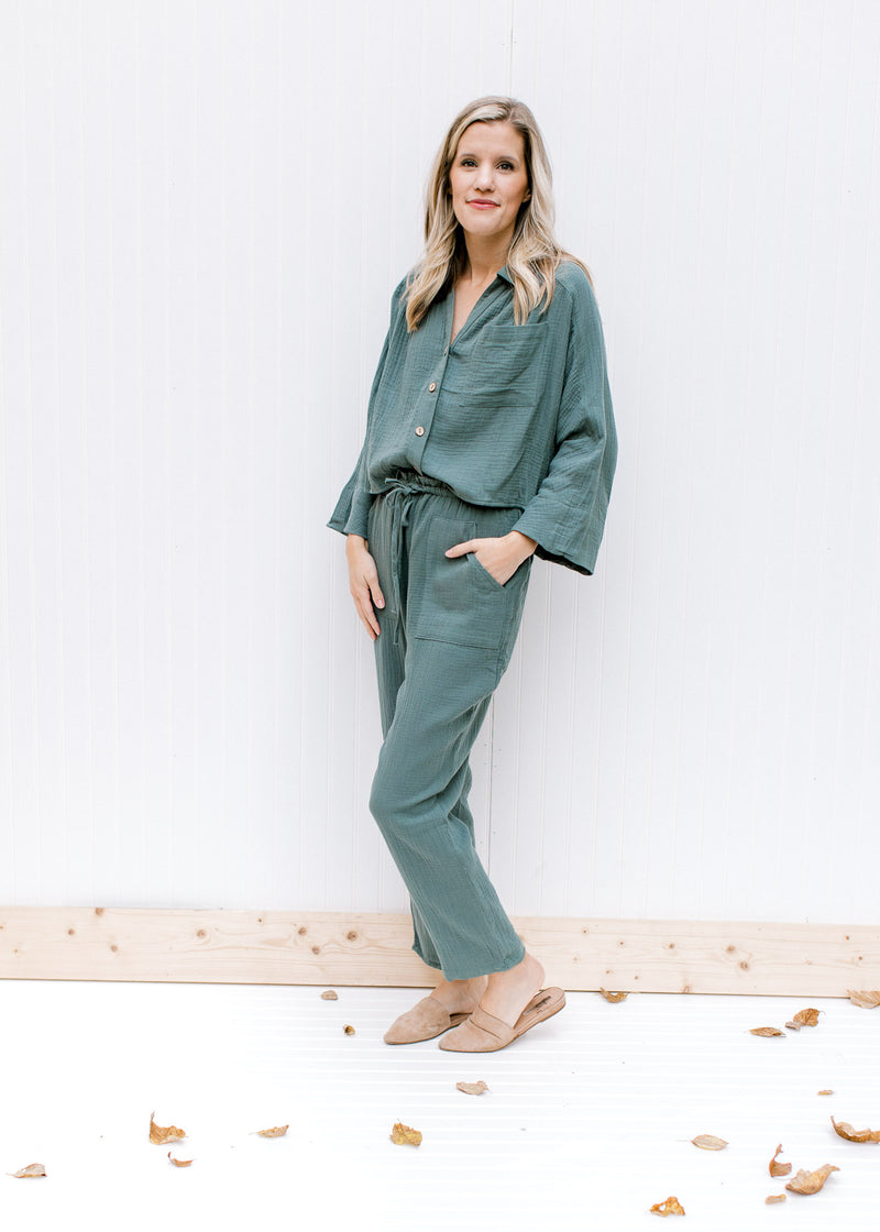Model wearing slides with a hunter green gauze set, top with button closure and bottom with tie. 