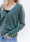 Close up of flower rhinestone buttons closure and cuff detail on a green long sleeve cardigan. 