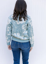 Back view of Model wearing a sage sweater with a cream design, long sleeves, and a crew neck. 