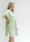 Side view of a model wearing a green above the knee dress with cuff short sleeve 