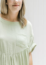 Close up of patch pocket and cuff short sleeves on a model in a green dress. 