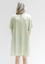 Back view of a green dress with a keyhole closure and cuff short sleeves. 