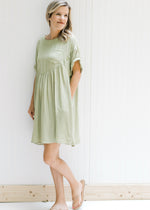 Model wearing a green dress with a patch pocket, cuff short sleeves and a keyhole closure. 
