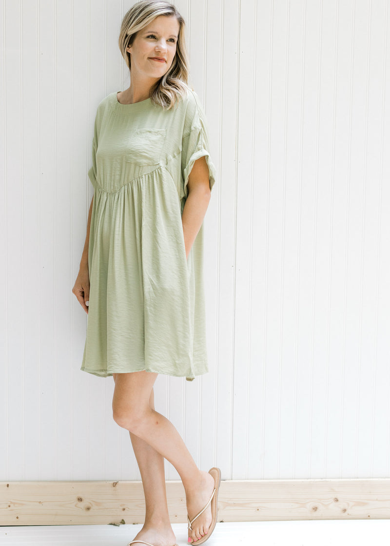 Model wearing a green dress with a patch pocket, cuff short sleeves and a keyhole closure. 