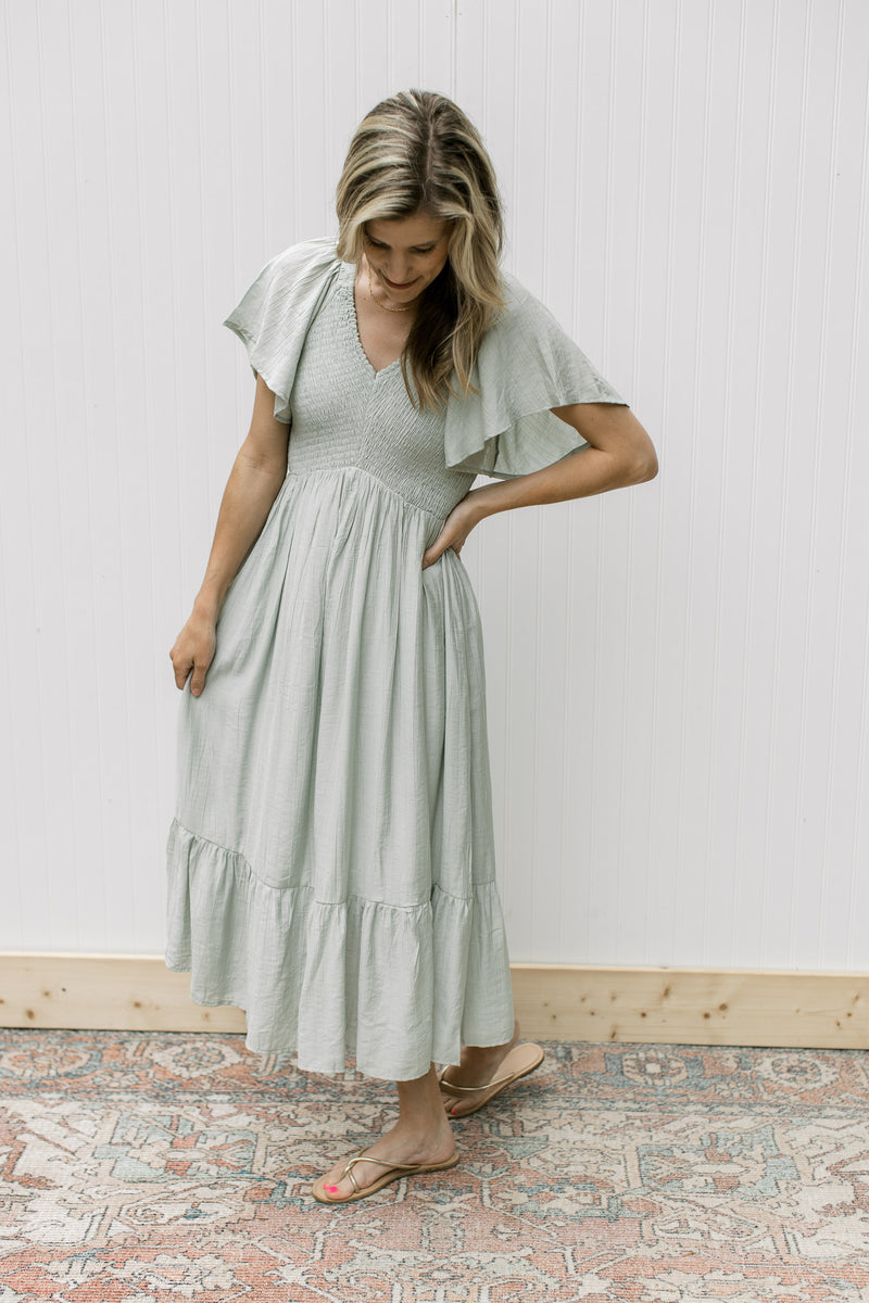 Model wearing sandals with a pale green maxi with a smocked bodice and flutter short sleeves.