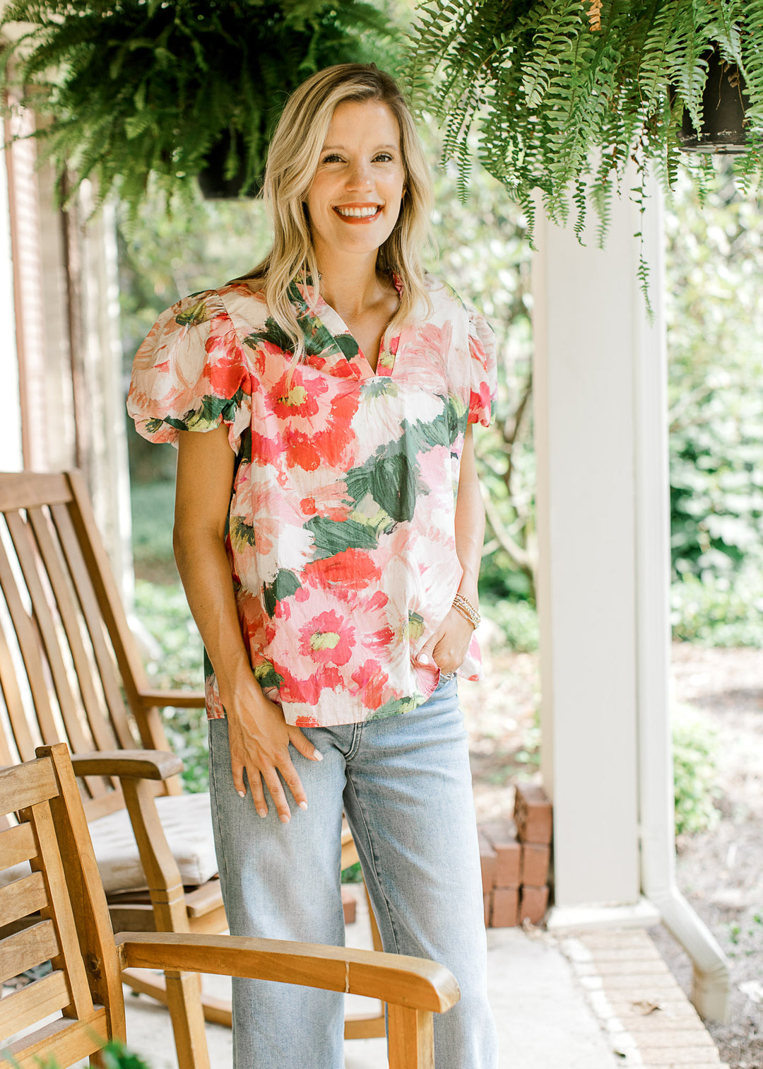 Model wearing a watercolor floral print top with short bubble sleeves and v-neck with ruffle.
