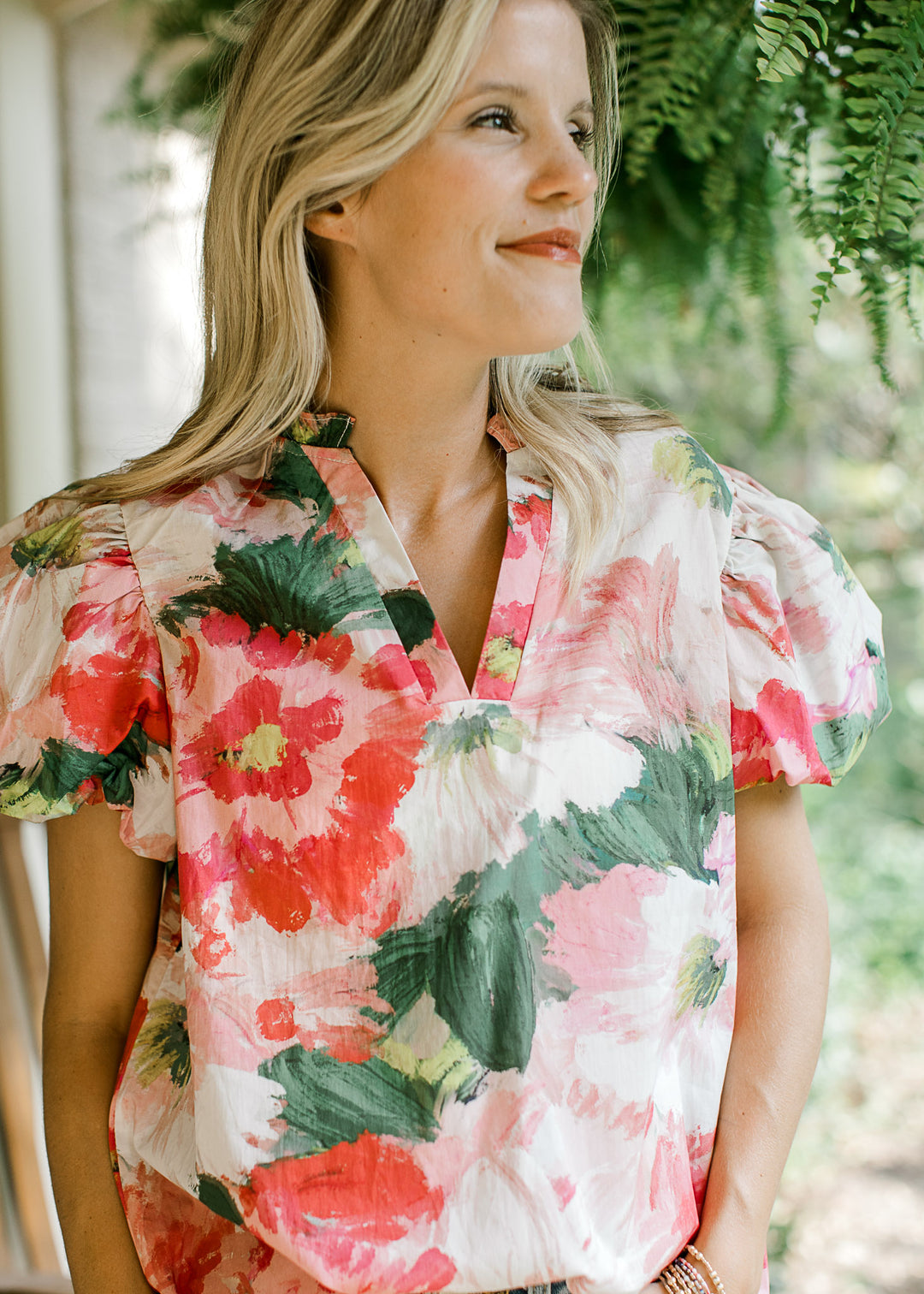 Close up on v-neck and bubble short sleeves on a watercolor floral blouse. 