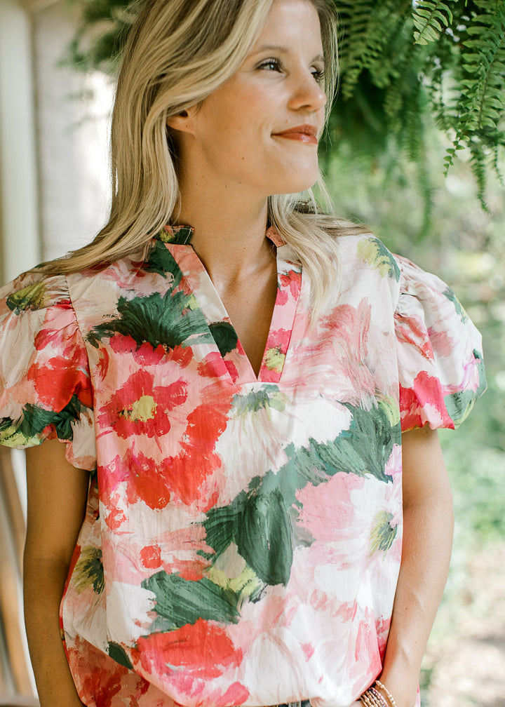 Close up on v-neck and bubble short sleeves on a watercolor floral blouse. 