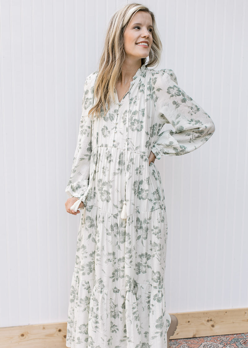 Model wearing a beige maxi with sage floral pattern, button front and long sleeves. 