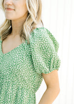 Close up of bubble sleeve on a cream dress wit a green microfloral pattern and a v-neck. 