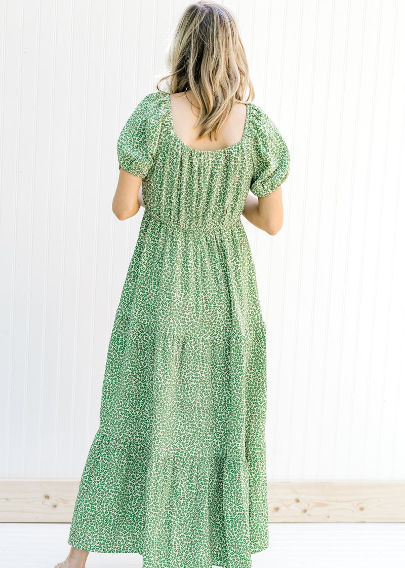 Back view of Model wearing a cream, maxi dress with a green microfloral pattern with a square back. 